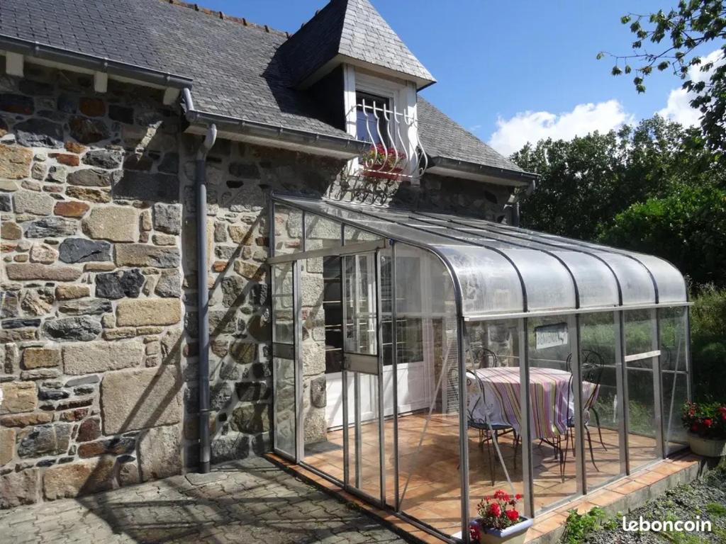 une serre sur le côté d'une maison en pierre dans l'établissement Gîte les Yards, à Yffiniac