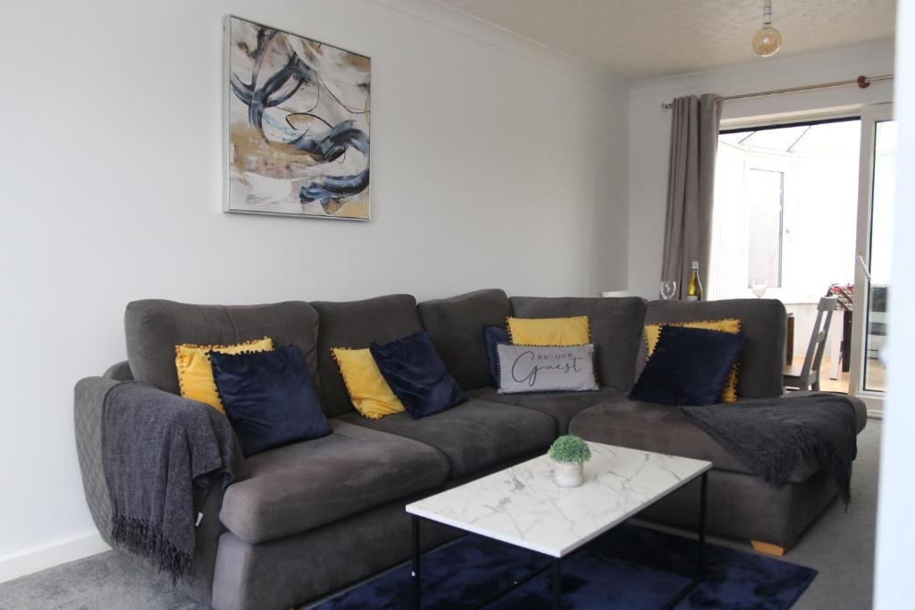 a living room with a brown couch with blue and yellow pillows at Comfy 2-Bedroom House in Parkgate - Ideal for Contractors/Business Travellers in Rotherham