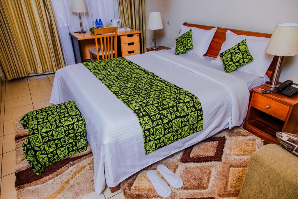 um quarto com uma cama grande com lençóis verdes e brancos em One Click Hotel em Kigali