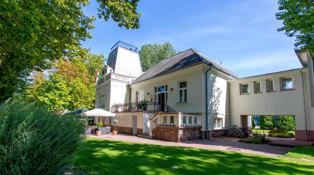 una gran casa blanca con un gran patio en Főnix Hotel, en Balatonföldvár