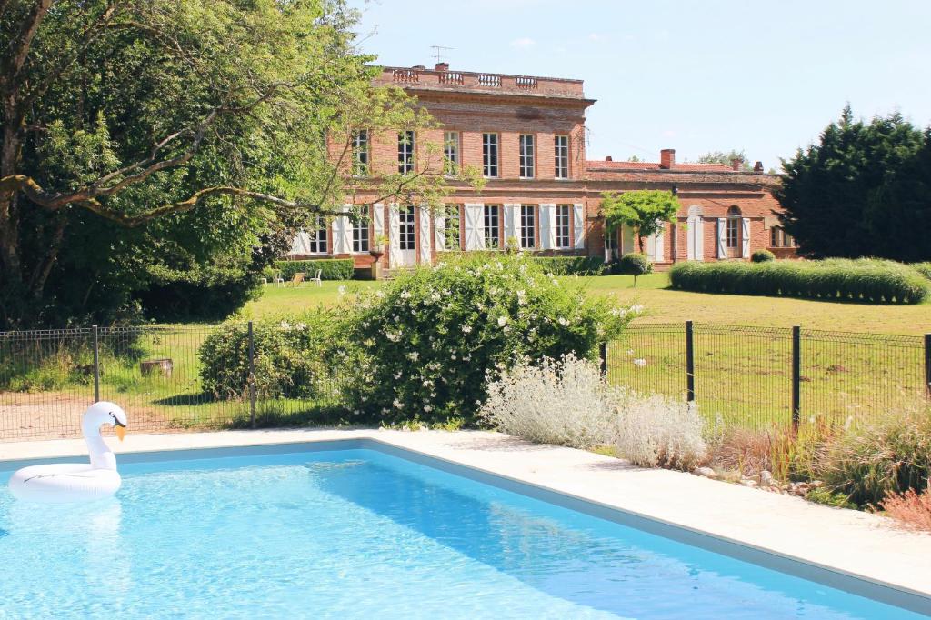 un cygne dans une piscine en face d'une maison dans l'établissement Chambre d'hôte double 2, à Castelsarrasin