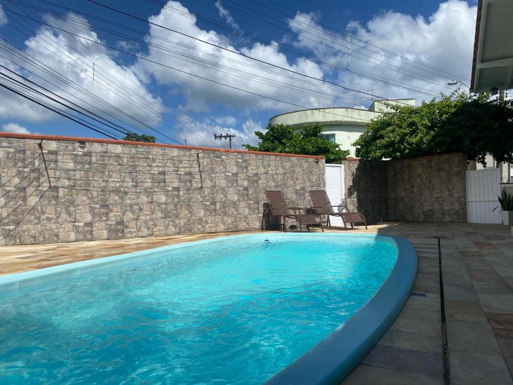 una piscina azul con 2 sillas y una pared de ladrillo en Blumen Espaço "piscina privativa' en Blumenau