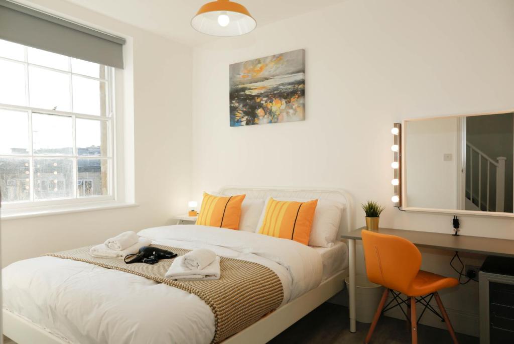 a white bedroom with a bed and a desk and window at Camden Town Self Check-in Luxury Rooms in London