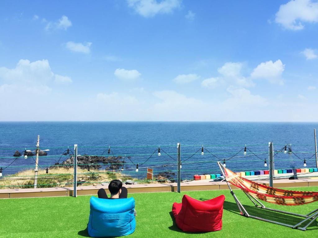 une femme assise sur des chaises donnant sur l'océan dans l'établissement Yesjun Guest house, à Jeju