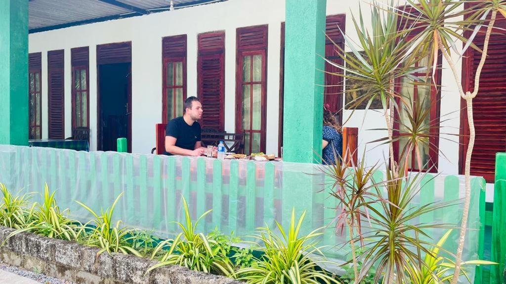 a man sitting at a table in front of a house at Jm Resort in Dambulla