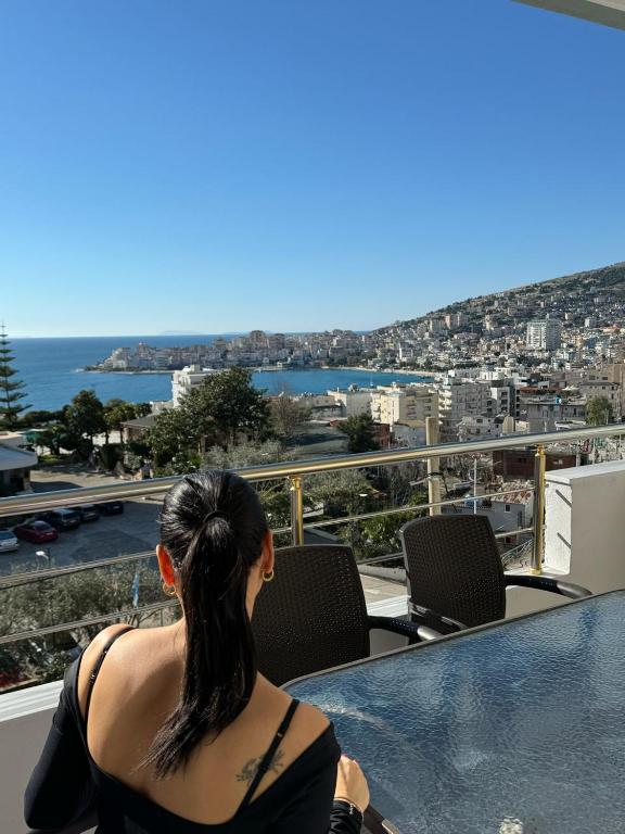 a woman sitting at a table looking at the ocean at Mimosa Luxury Apartment in Sarandë
