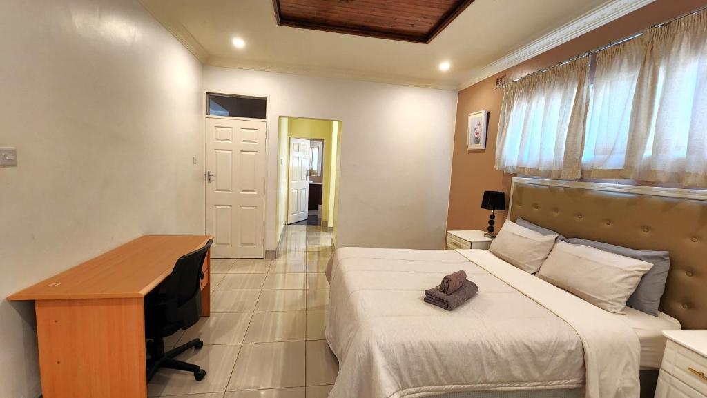 a bedroom with a bed and a desk and a television at Grey Oak Holiday House in Bulawayo