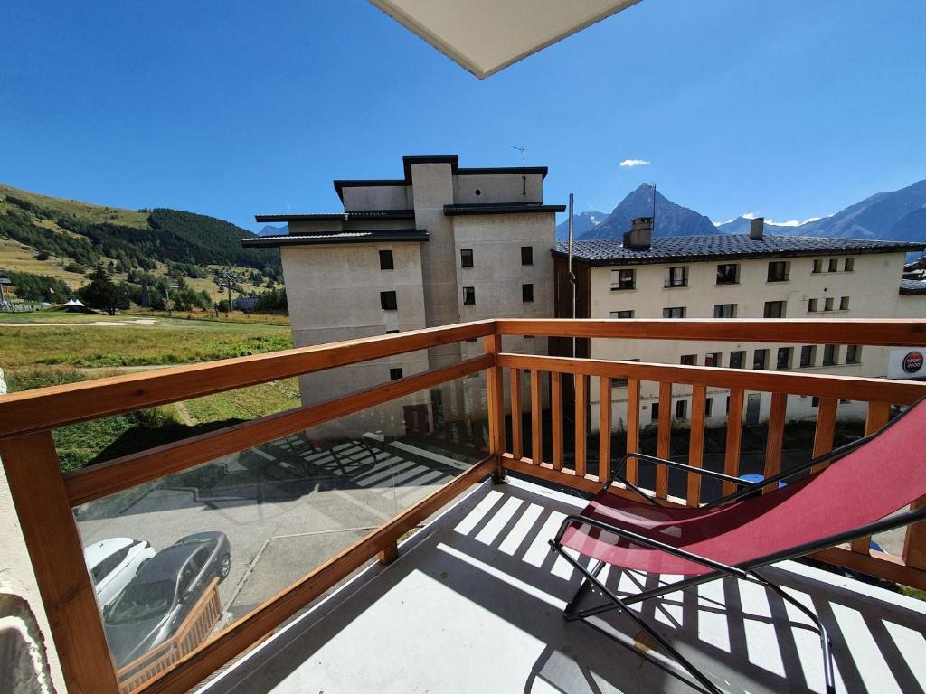 une chaise sur un balcon avec vue sur un bâtiment dans l'établissement Le 3300 - 20 - Appart expo sud - 6 pers, à Les Deux Alpes