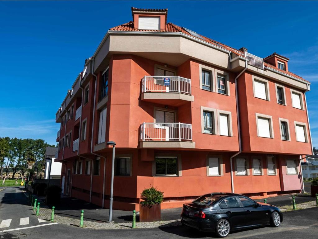 ein rotes Gebäude mit einem davor geparkt in der Unterkunft Apartment Edificio Bahia II by Interhome in Miño