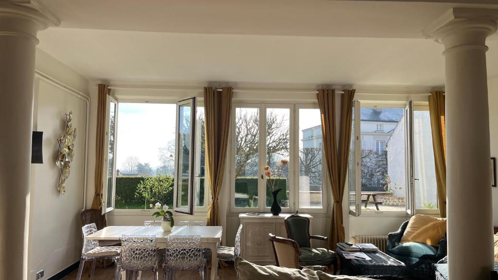 sala de estar con mesa, sillas y ventanas en appartement lumineux, en Montfort-lʼAmaury