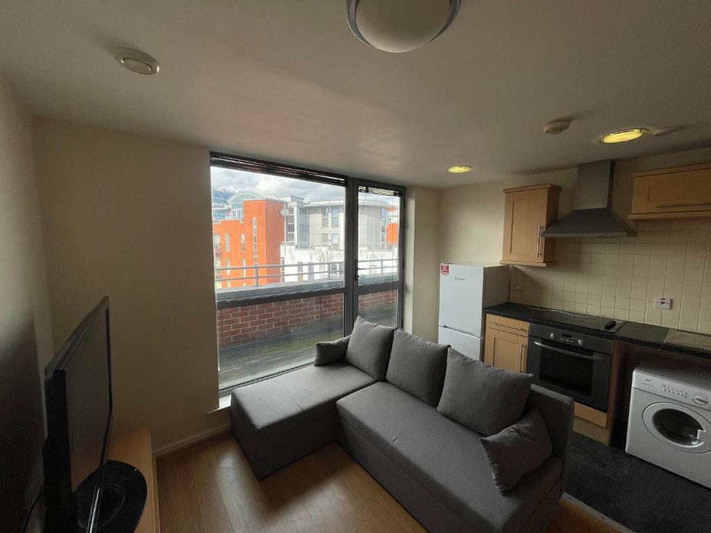 a living room with a couch and a large window at Immaculate 2-Bed Duplex Apartment in Leeds in Leeds