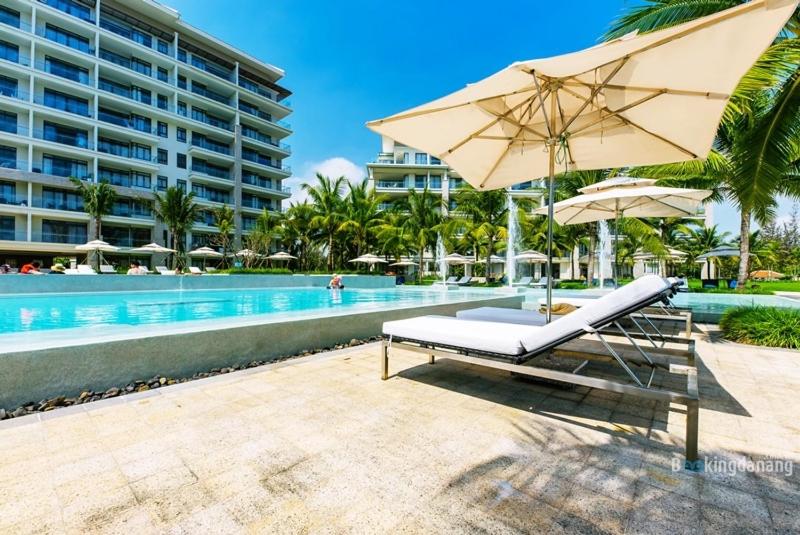 a beach chair with an umbrella next to a swimming pool at Ocean Apartment Two Bedrooms in Danang