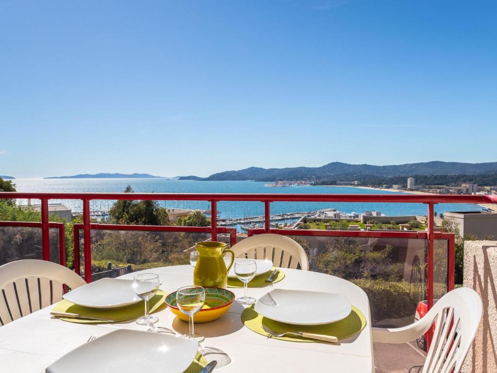 Una mesa blanca con sillas y vista al agua. en Apartment Les Mandariniers by Interhome, en Le Lavandou