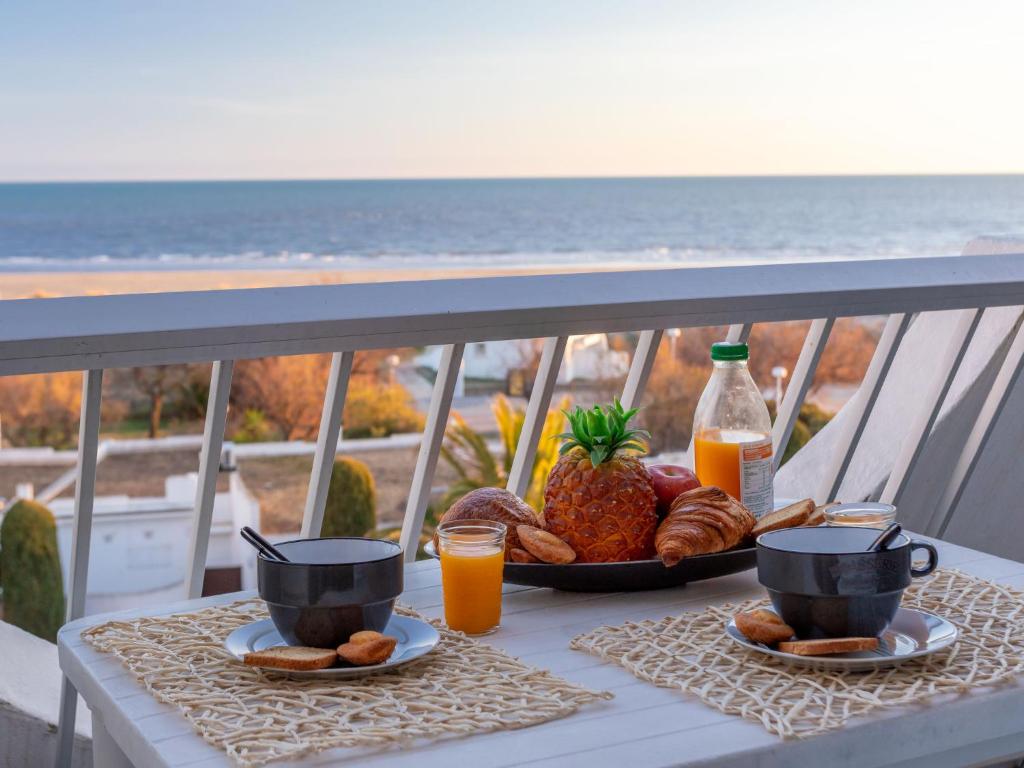 a table with a tray of food on a balcony with the beach at Apartment La Calypso-6 by Interhome in La Grande-Motte