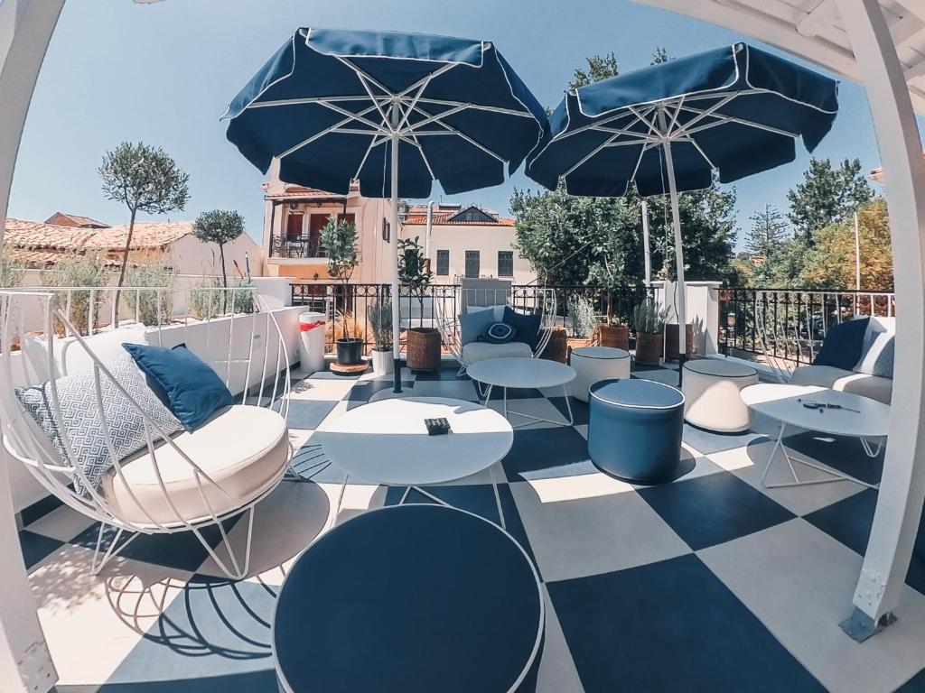普雷韋扎的住宿－BLUE LUXURY SUITES，一个带桌椅和遮阳伞的庭院