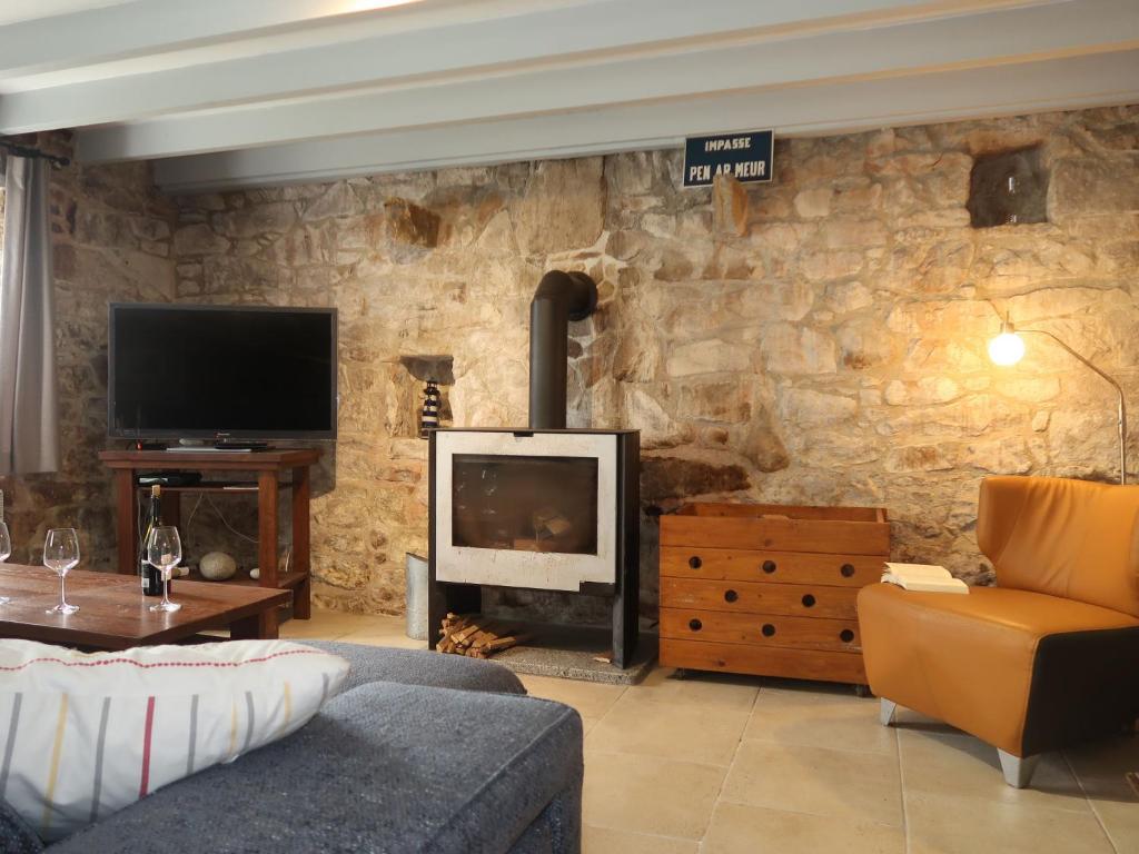 sala de estar con pared de piedra y chimenea en Holiday Home L&#39;Iroise by Interhome, en Plogoff