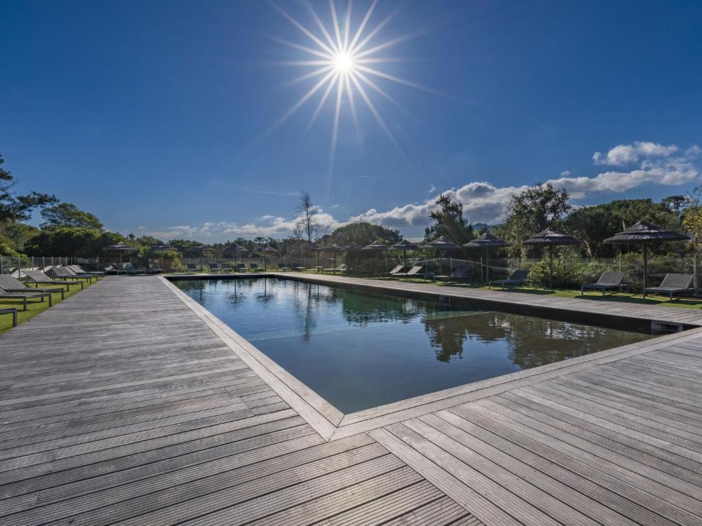 une piscine dans un parc avec le soleil dans le ciel dans l'établissement Apartment Cala Sultana-16 by Interhome, à Porto-Vecchio