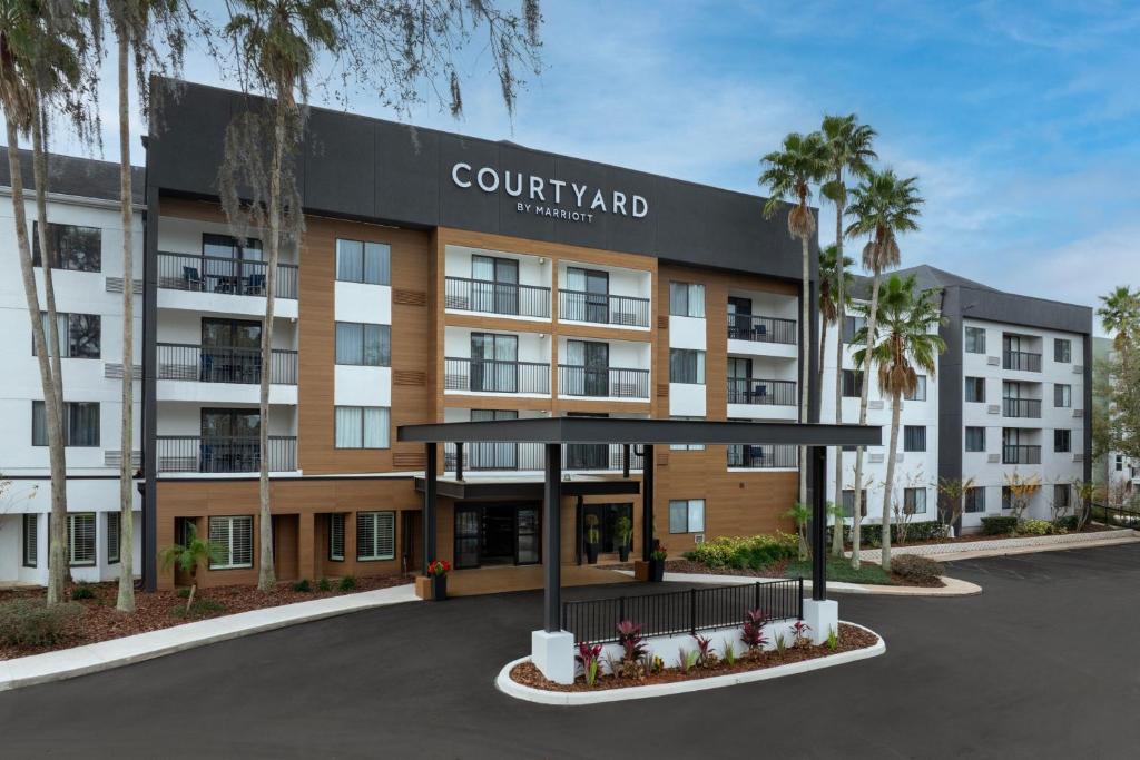 a rendering of a courtyard hotel with palm trees at Courtyard by Marriott Orlando East/UCF Area in Orlando