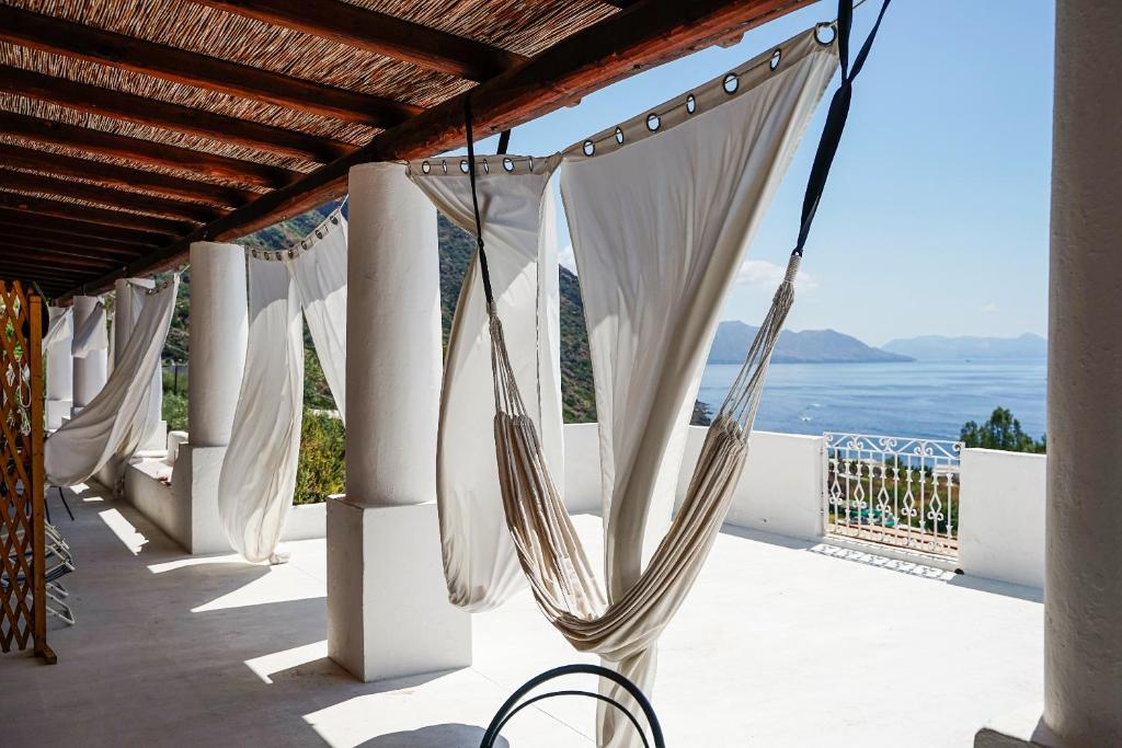uma fila de cortinas brancas numa varanda com o oceano em Salina Castel Vinci em Rinella