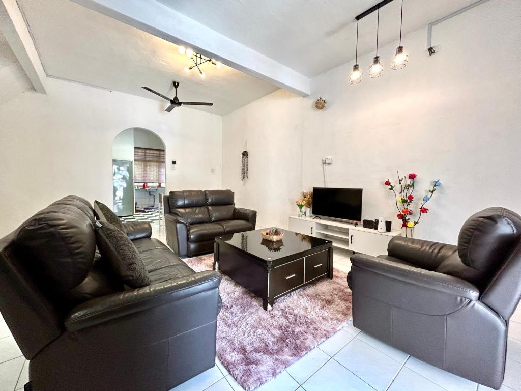 uma sala de estar com mobiliário de couro e uma televisão de ecrã plano em Cozy 10 Entire House 4 Bedroom At Alma Bukit Mertajam em Bukit Mertajam