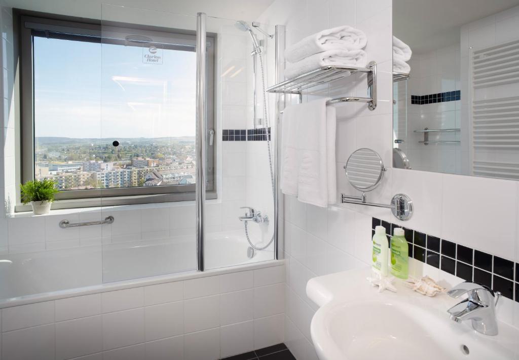 a white bathroom with a shower and a sink at Clarion Congress Hotel České Budějovice in České Budějovice