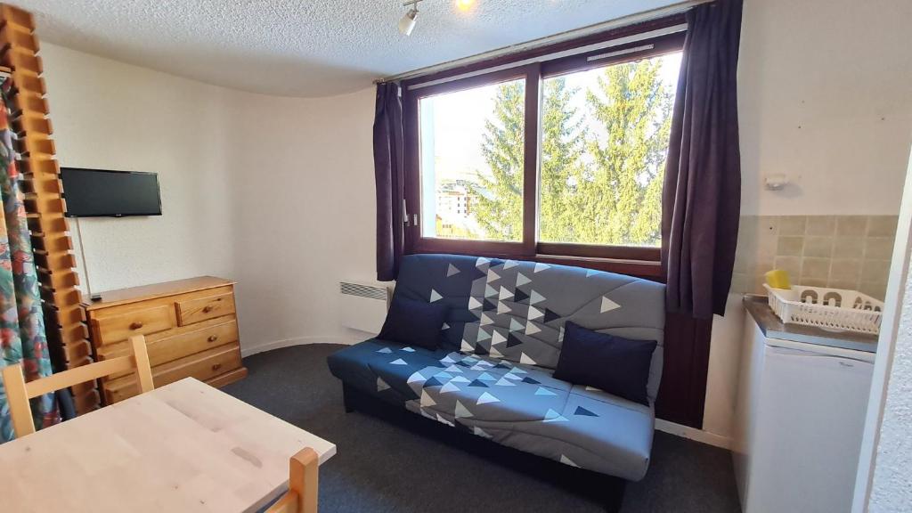 ein kleines Zimmer mit einem blauen Sofa und einem Fenster in der Unterkunft Le 3300 - 42 - Studio vue piste - 2 pers in Les Deux Alpes