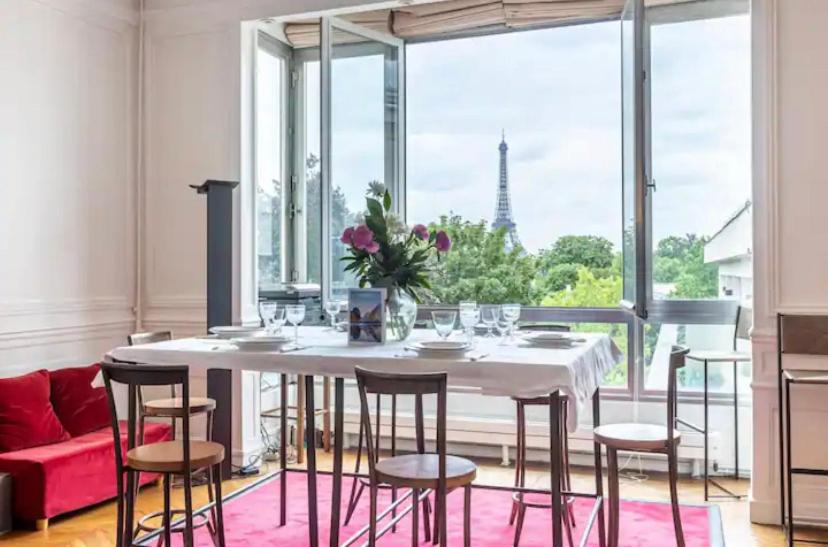 a dining room with a table and chairs and a large window at 4 bedroom Luxury Eiffel Tower Apartment in Paris