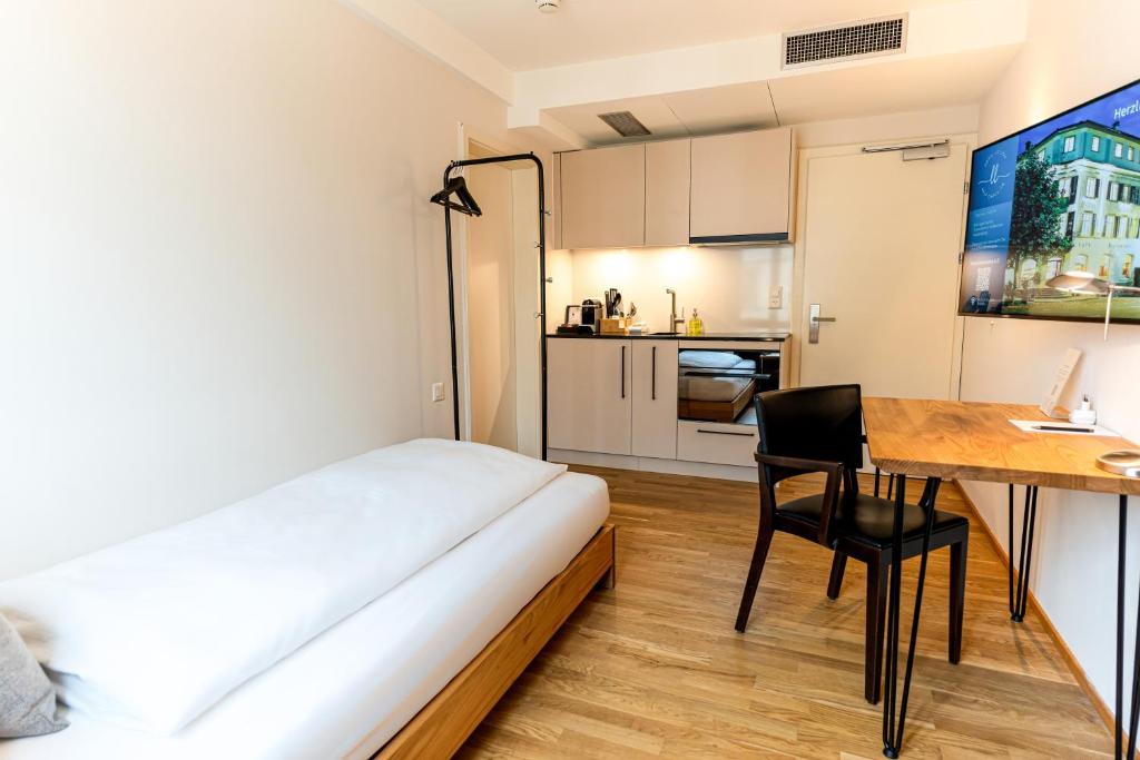 Kleines Zimmer mit einem Bett, einem Schreibtisch und einer Küche in der Unterkunft Hotel Le Lion - Self Check-in in Bischofszell