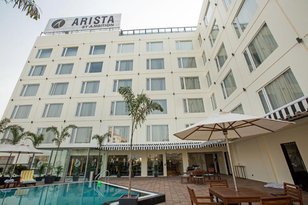 a hotel with a swimming pool in front of a building at ARISTA BY AMBITION in Guwahati