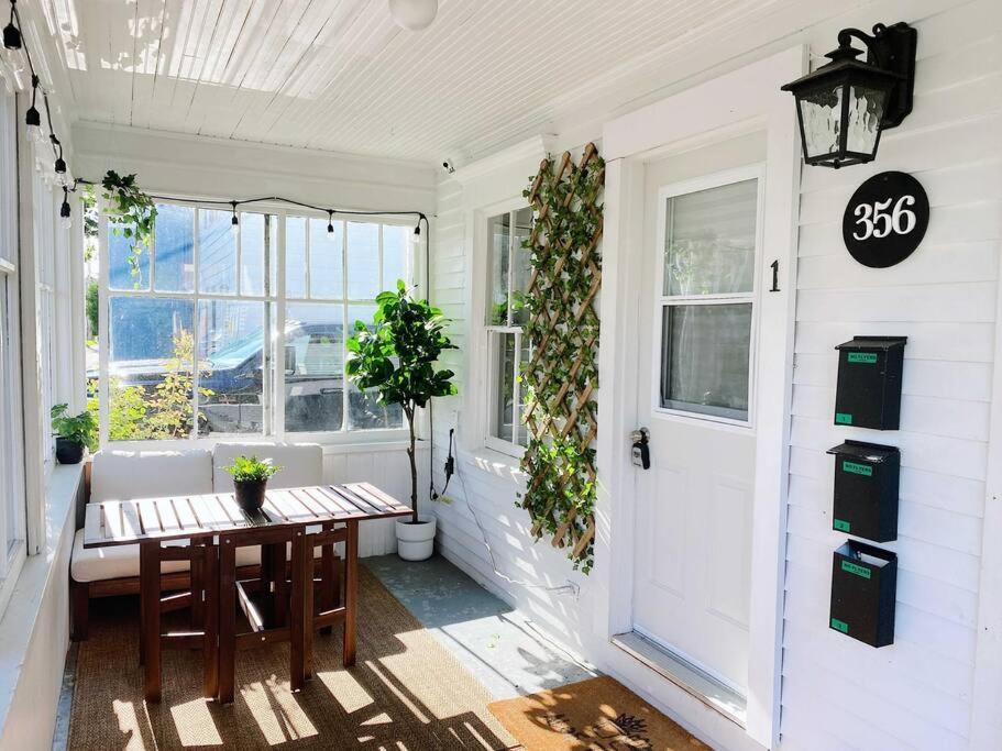 un porche con una mesa y una puerta con plantas en The LOCAL BREW Perfect For FOODIES + BEER LOVERS, en Fredericton