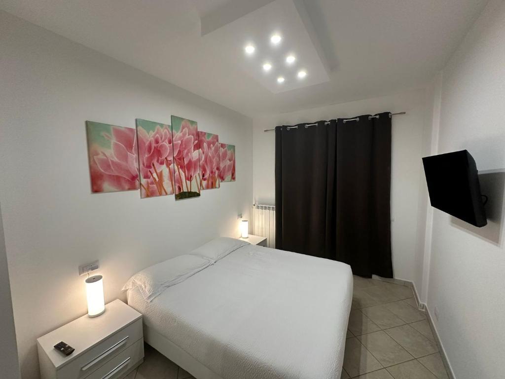 a bedroom with a white bed and a tv at Ciclamino Appartamento Roma in Infernetto