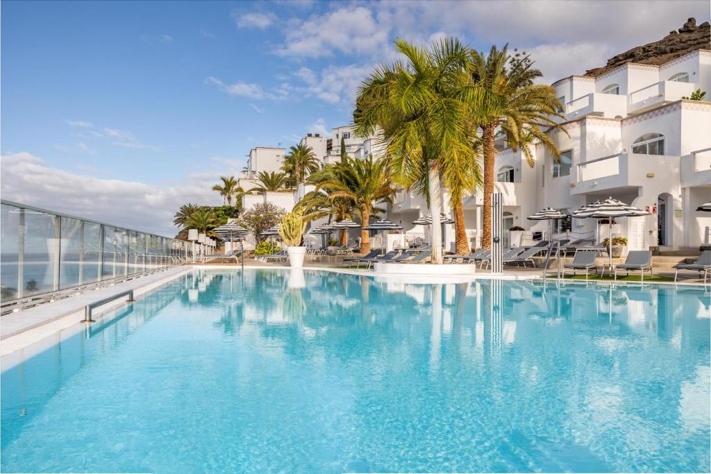 une grande piscine avec des palmiers et des bâtiments dans l'établissement Marina Bayview Gran Canaria - Adults Only, à Puerto Rico