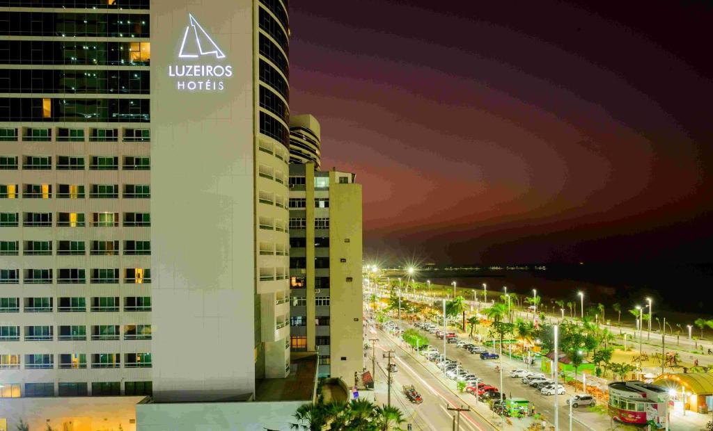 a building with a sign on it next to a street at Hotel Luzeiros Fortaleza in Fortaleza