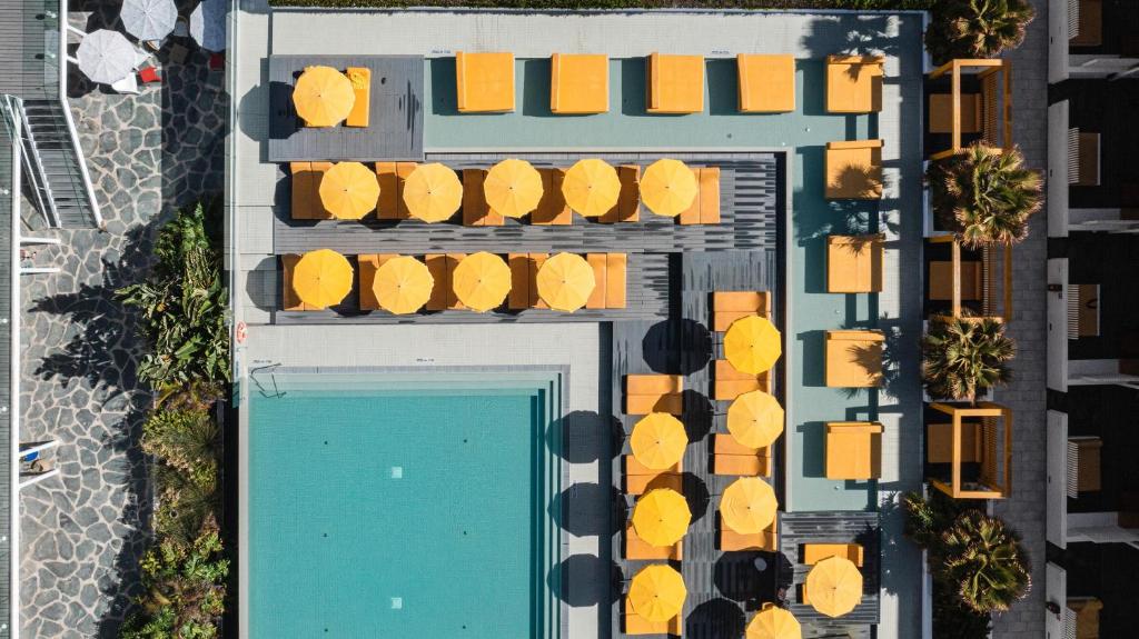 una vista aérea de una piscina con sillas amarillas en Buendía Corralejo nohotel en Corralejo