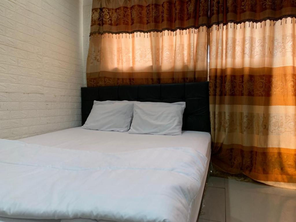 een bed in een kamer met een raam met witte lakens bij RedLiving Apartemen Sentra Timur - YN Idea Property Tower Kuning in Jakarta