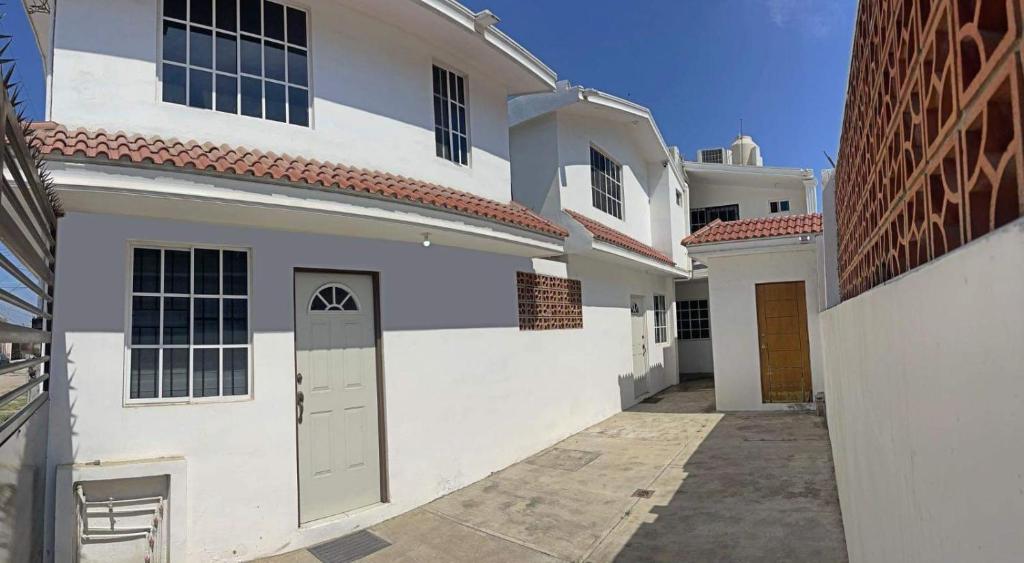 uma casa branca com uma porta e um edifício em Apartamentos Tampico-Altamira 