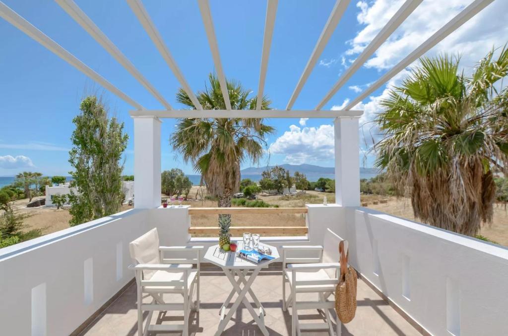 a patio with a table and chairs and palm trees at Glaronissi Beach in Plaka