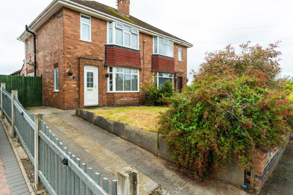 a brick house with a fence in front of it at Heath House in Burton upon Trent