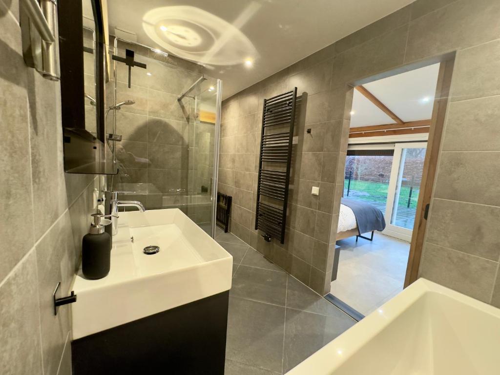 een badkamer met een wastafel, een douche en een bad bij De Seuterhoeve in 's-Gravendeel