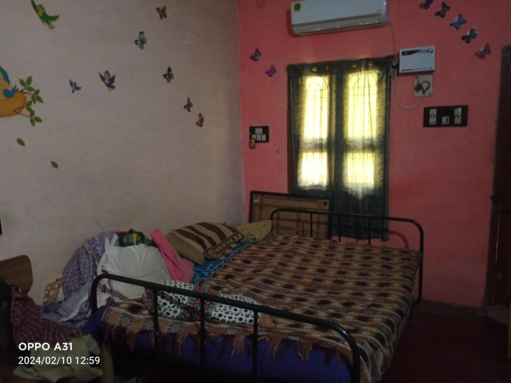 a bedroom with a bed and a window with butterflies on the wall at Shanthi Illam in Madurai