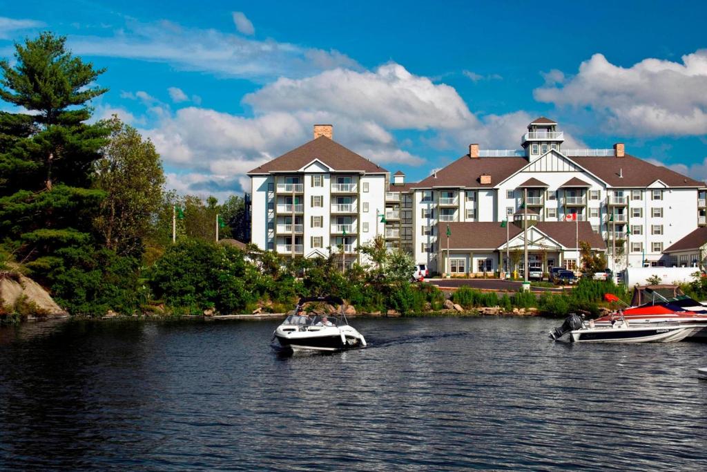 dois barcos na água em frente a um hotel em Residence Inn by Marriott Gravenhurst Muskoka Wharf em Gravenhurst