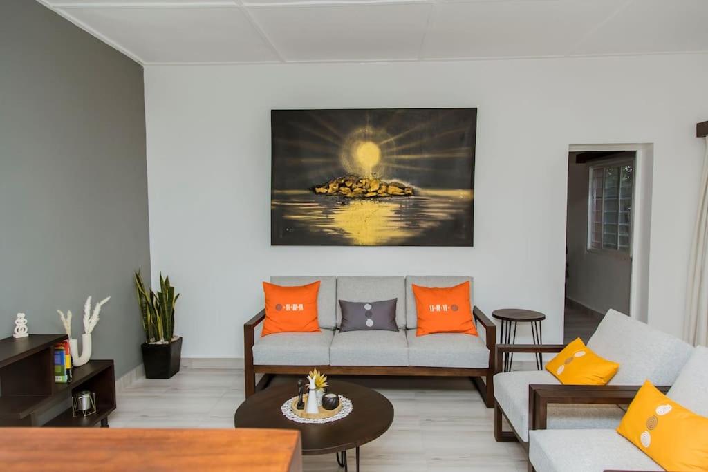 a living room with a couch and orange pillows at Neza Haven Kigali in Kigali