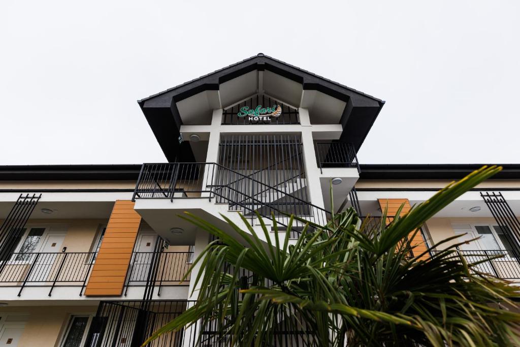 an apartment building with a balcony and a palm tree at Safari Hotel in Szeged