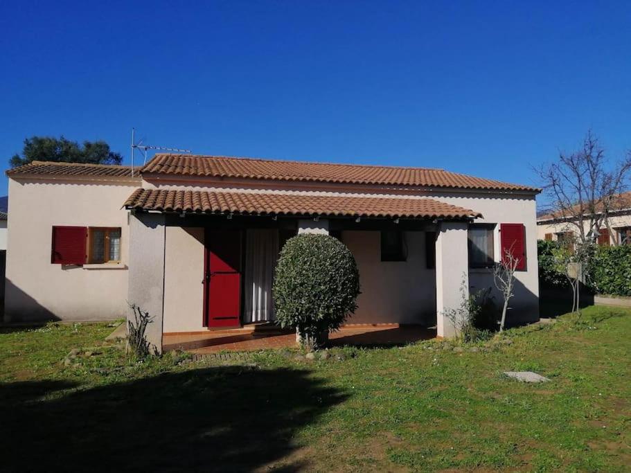 une petite maison blanche avec des portes rouges et une cour dans l'établissement Maison près de la plage, à Penta-di-Casinca
