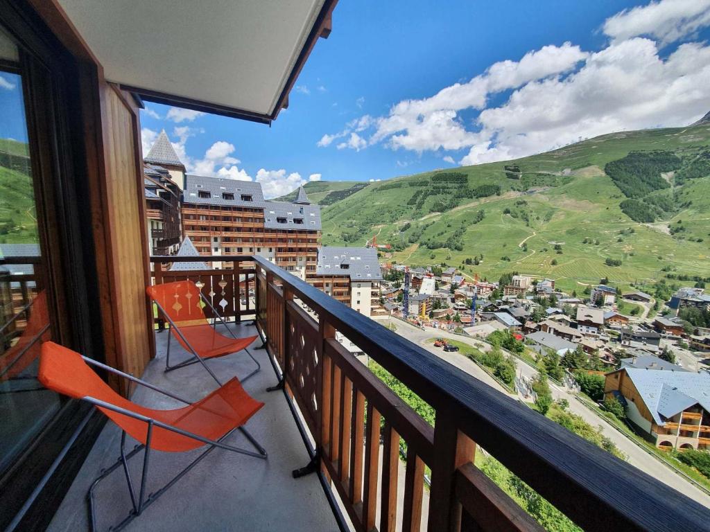 un balcon avec deux chaises et une vue sur une ville dans l'établissement Le Soleil - 412 - Appart belle vue - 4 pers, à Les Deux Alpes