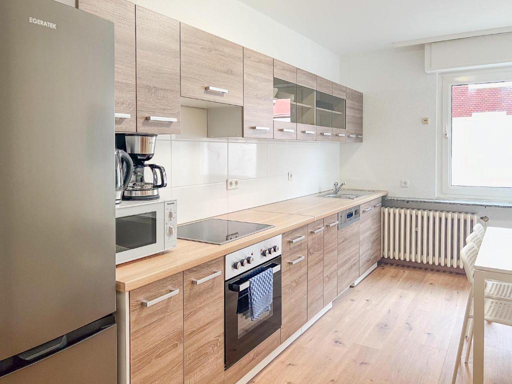 eine Küche mit Holzschränken und Geräten aus Edelstahl in der Unterkunft T&K Apartments - Duisburg - 3 Zimmer Apartment in Duisburg