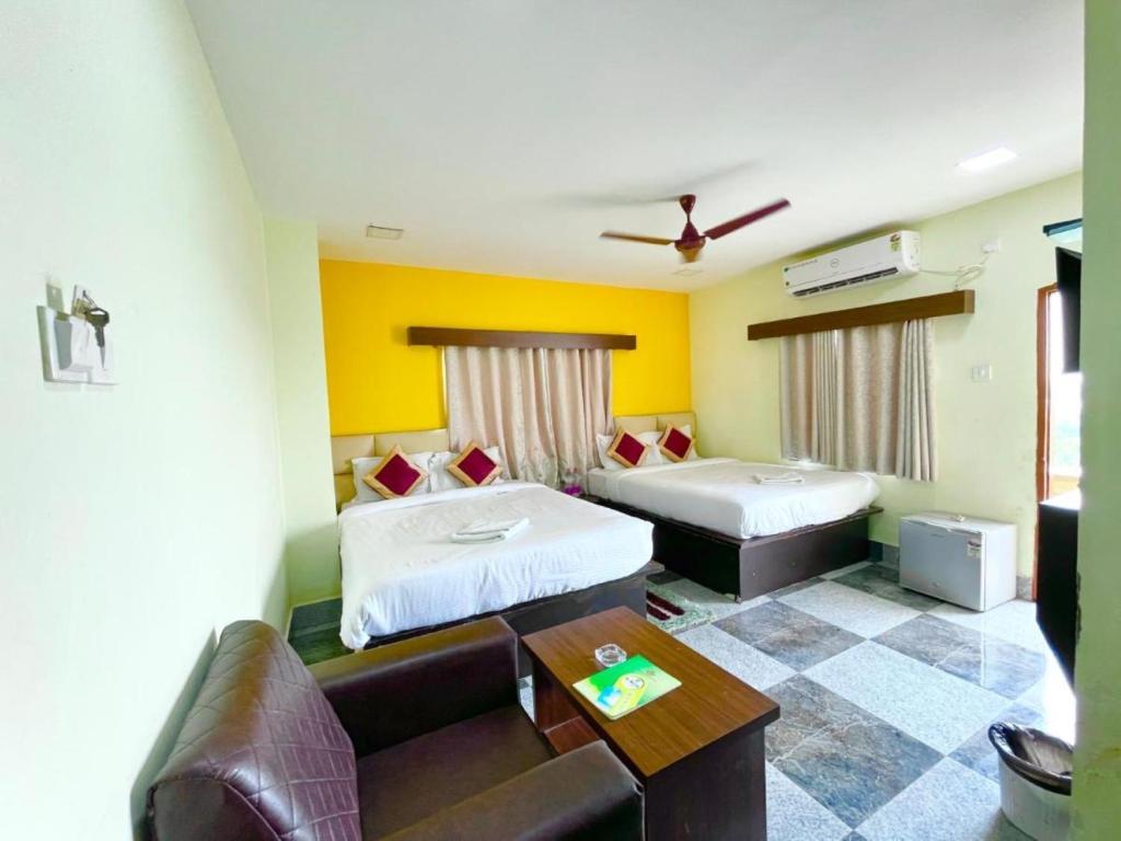um quarto de hotel com duas camas e um sofá em Goroomgo Coral Suites Puri Near Sea Beach with Swimming Pool - Parking Facilities em Puri