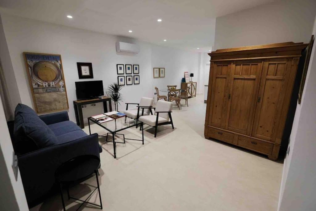 sala de estar con sofá azul y sillas en CoLet Apartamento, en Sevilla