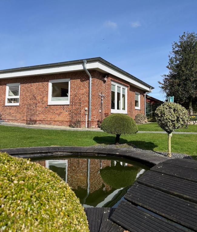 a brick house with a pond in front of it at Ferienwohnung Alida in Niebüll