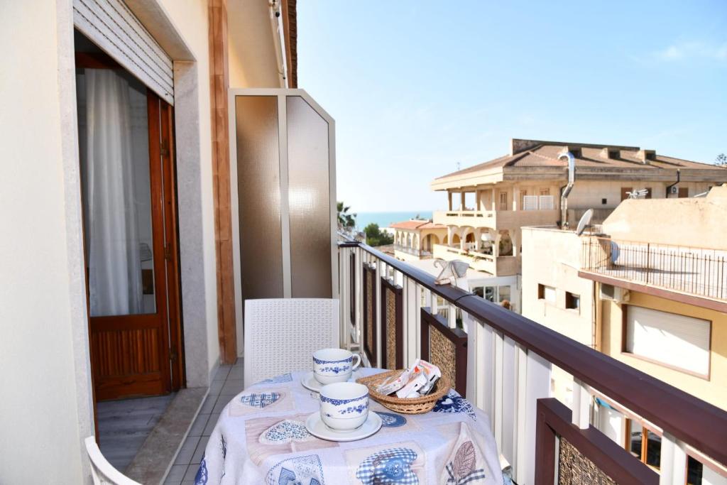 a balcony with a table with a table cloth and cups at BLU HOUSE in Marina di Modica
